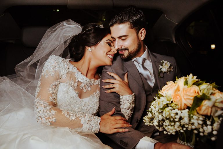 casamento Ângela e Rodrigo noivos recém-casados no carro com o noivo segurando o bouquet e a noiva sorrindo no colo dele