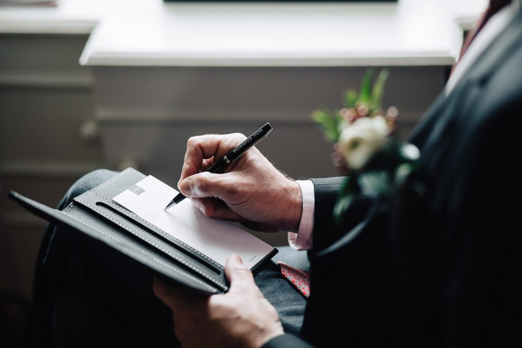 detalhes da mão e a caneta do noivo escrevendo seus votos