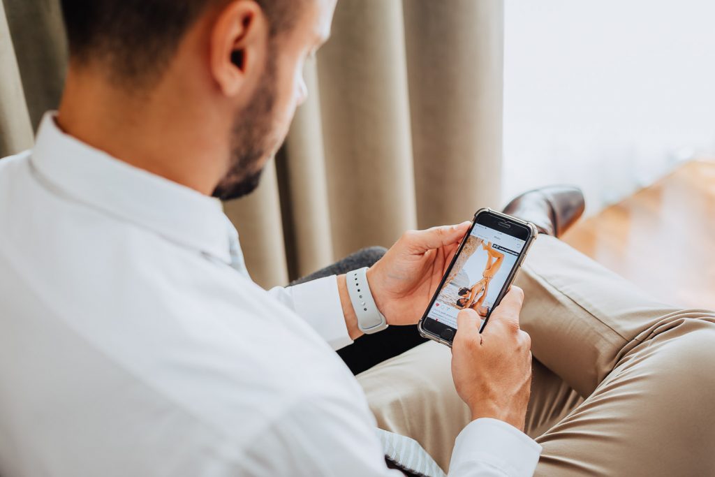 destination wedding palácio estoi noivo olhando para seu celular com foto do ensaio