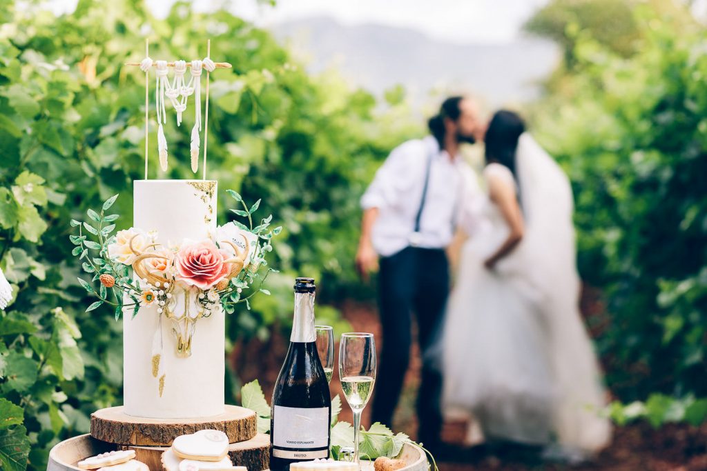 elopement boho quinta de alcube o bolo na frente e o casal desfocado se beijando