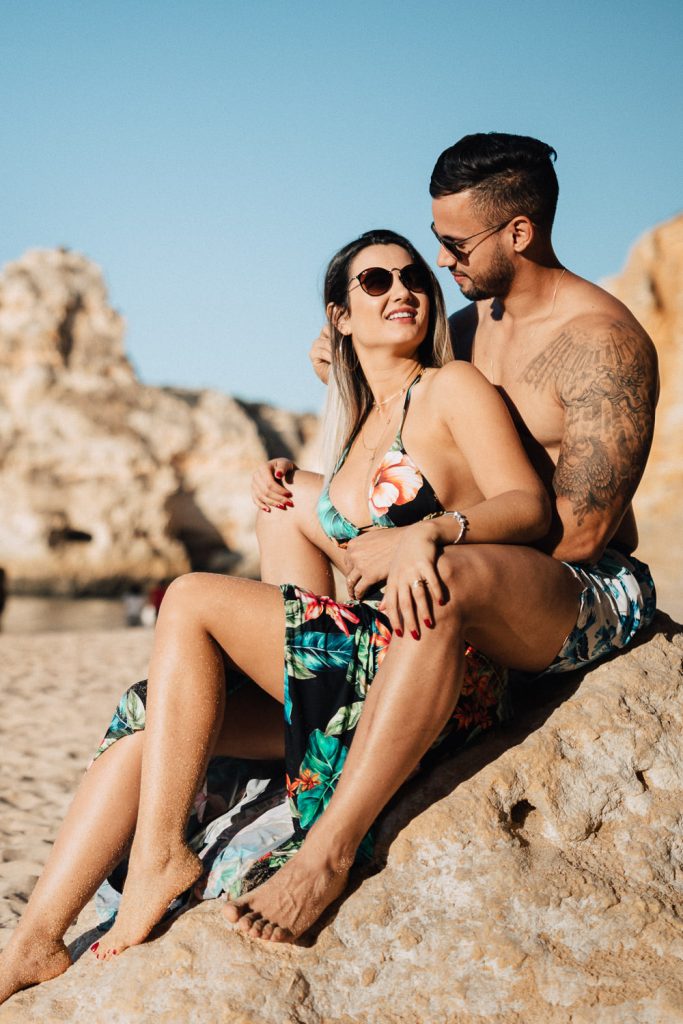 ensaio-praia-da marinha casal em cima de uma pedra ele acariciando os cabelos dela
