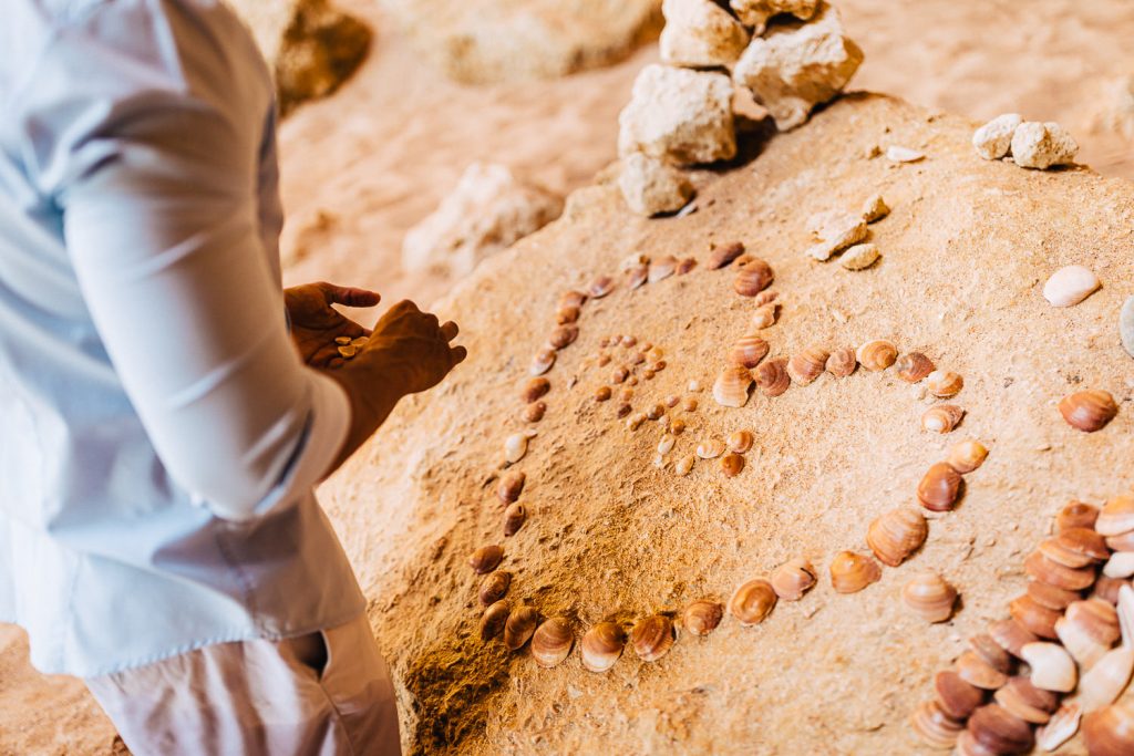 ensaio gruta benagil ele fazendo um coração de conchas marinhas
