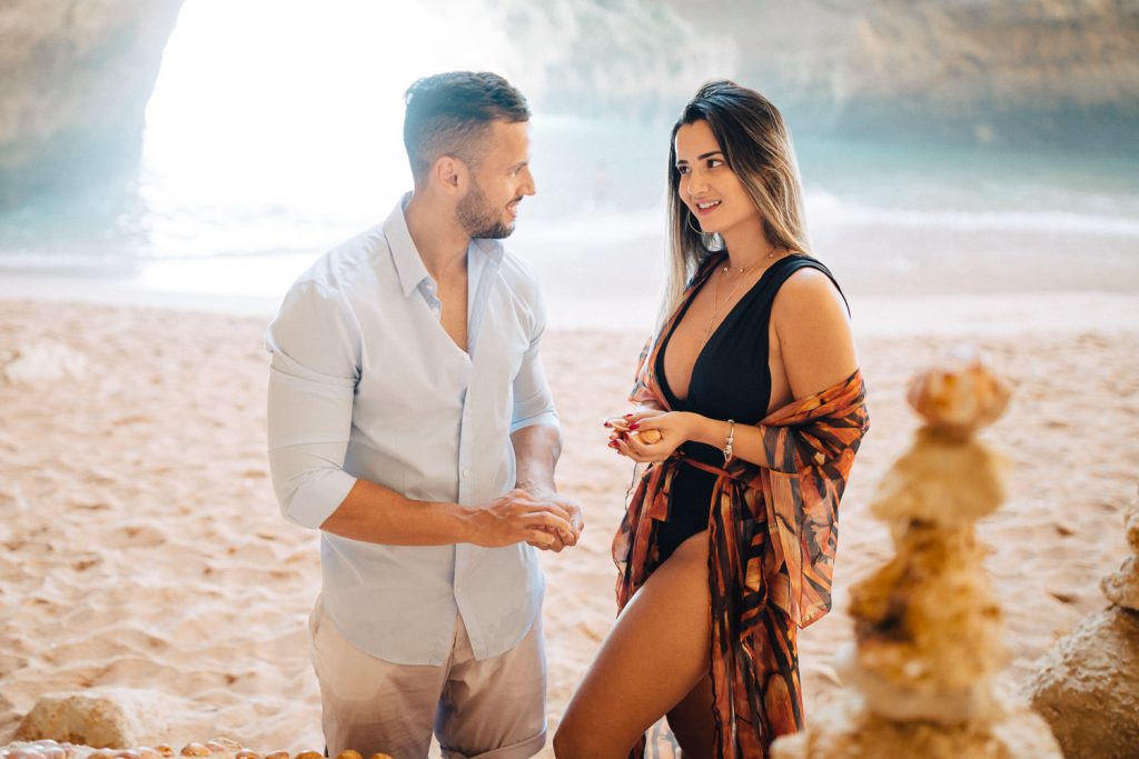 ensaio gruta benagil casal se olhando em quando estão escrevendo com conchas