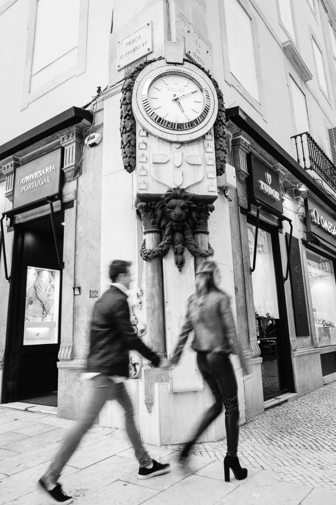 casal passeando perto de um relógio rolex grande