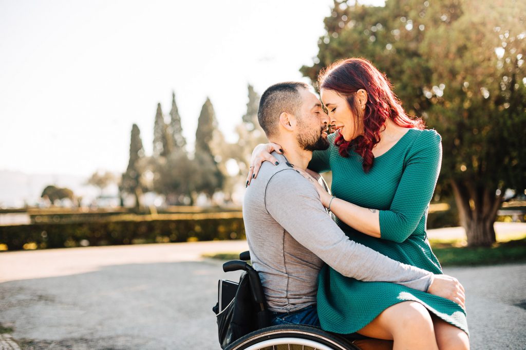 noiva sentada no colo do noivo na cadeira de rodas e se olhando em um parque de Lisboa Portugal