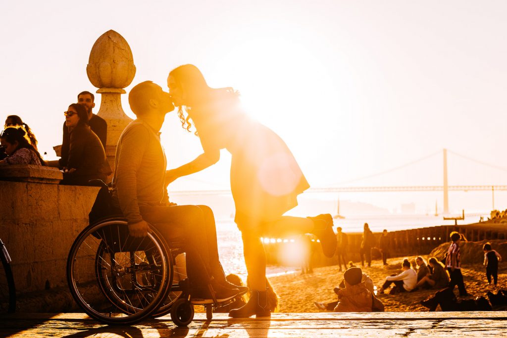 beijo do casal com por do sol ao fundo e aparecendo a ponte 25 de abril em Lisboa