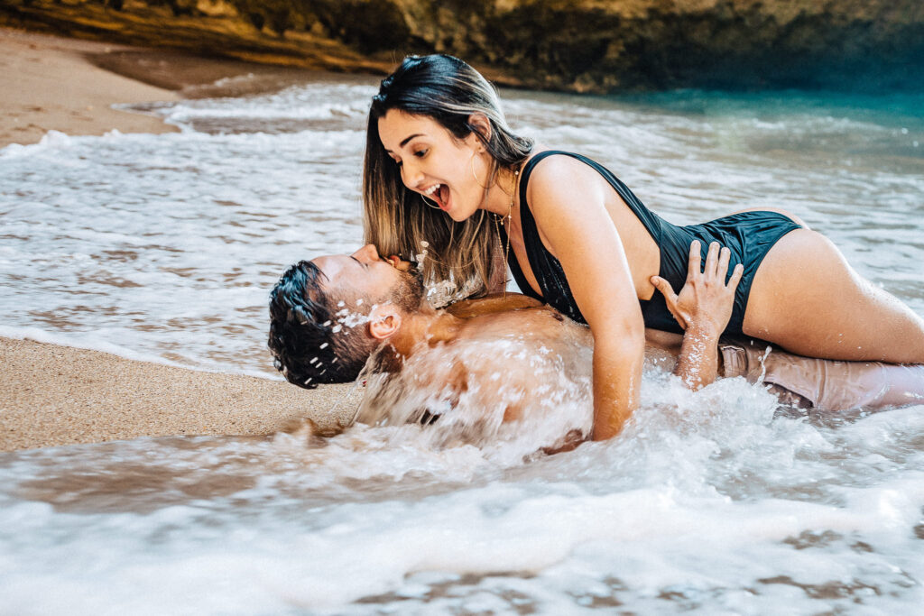 Ensaio pre wedding na gruta de benagil casal deitado e se molhando no mar